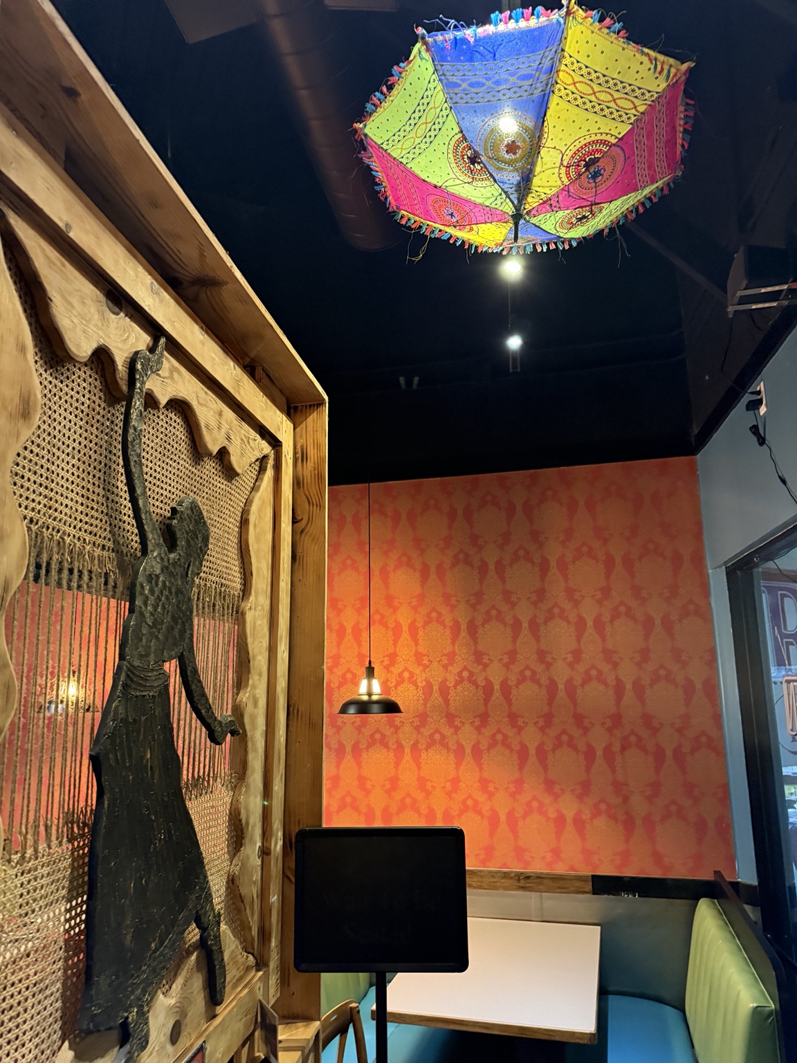 Indian Masala booth with orange patterned wall and hanging umbrella